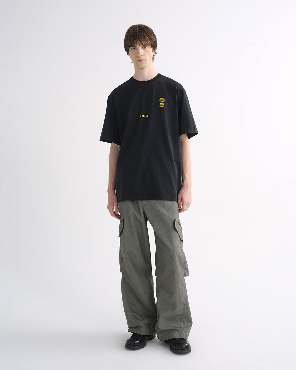 Person wearing black graphic T-shirt and grey cargo pants, front three-quarter view