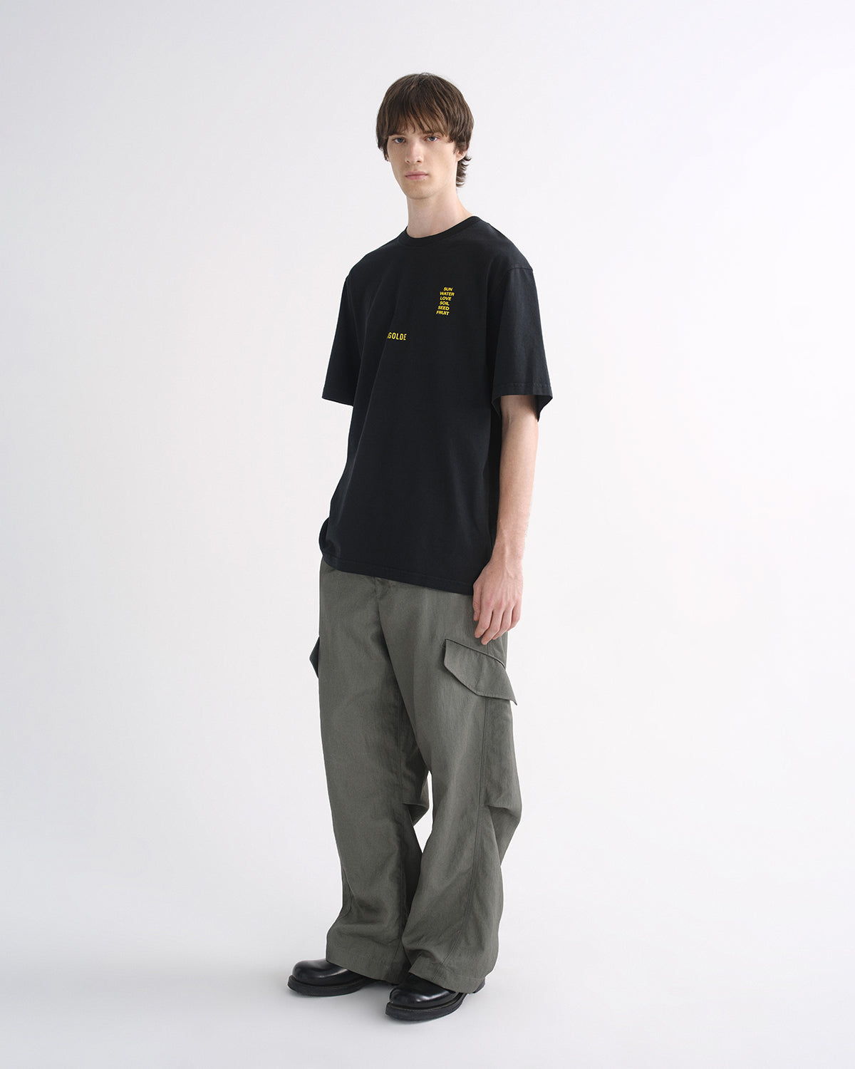 Person wearing black graphic T-shirt and grey cargo pants, alternate front view