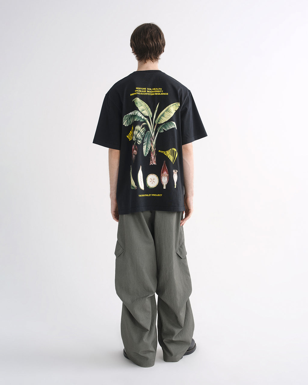 Person wearing black graphic T-shirt and grey cargo pants, back view
