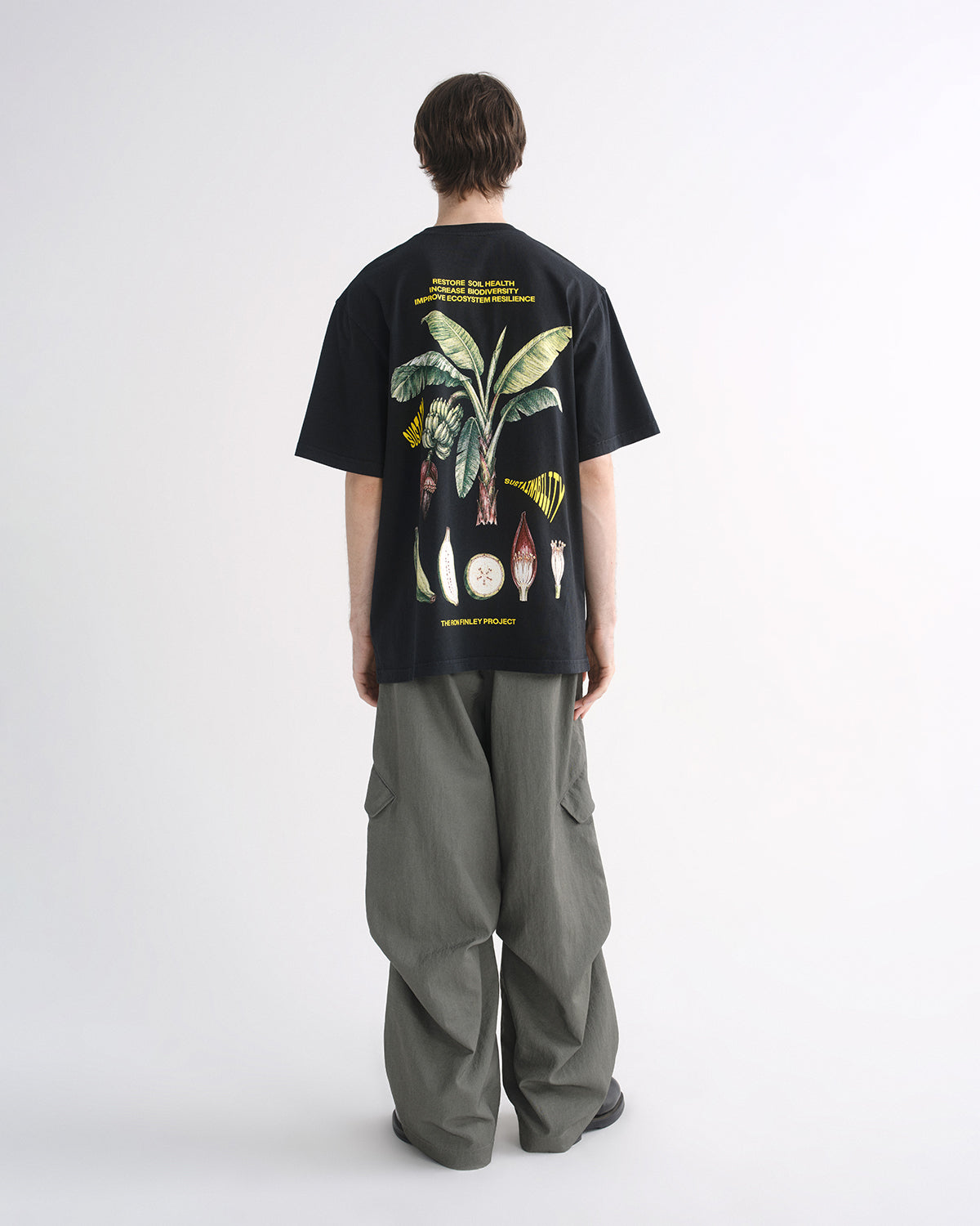 Person wearing black graphic T-shirt and grey cargo pants, back view