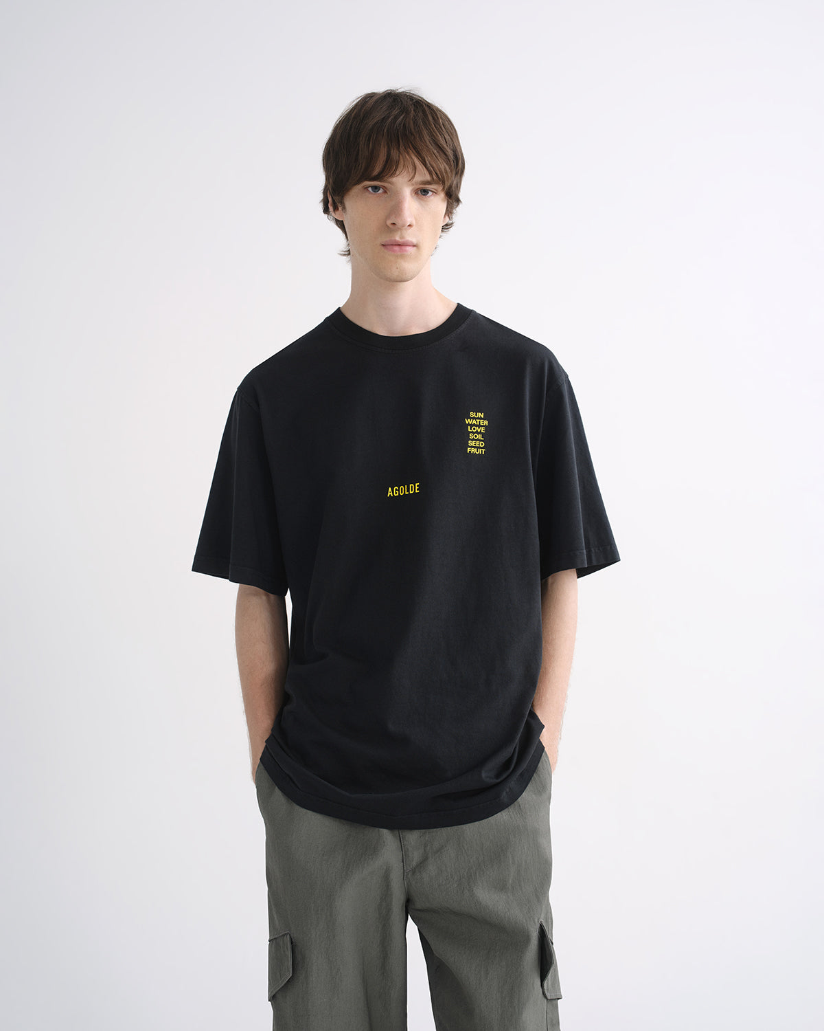 Person wearing black graphic T-shirt and grey cargo pants, front view