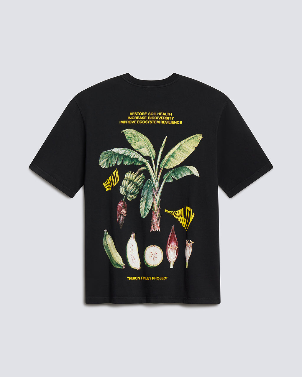 A black short-sleeve graphic T-shirt laid flat against a light gray background. The front features a large botanical illustration of a banana plant with green leaves, yellow flower elements, and white/pink fruit details, plus small yellow text above and below the artwork.
