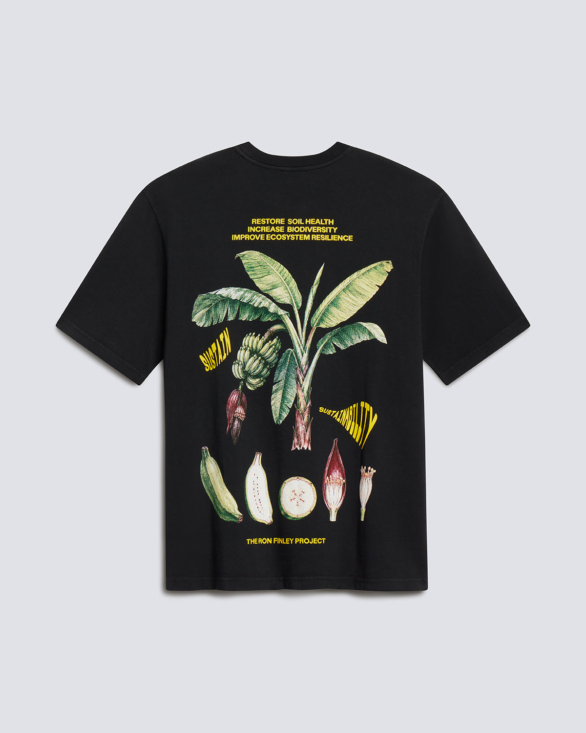 A black short-sleeve graphic T-shirt laid flat against a light gray background. The front features a large botanical illustration of a banana plant with green leaves, yellow flower elements, and white/pink fruit details, plus small yellow text above and below the artwork.