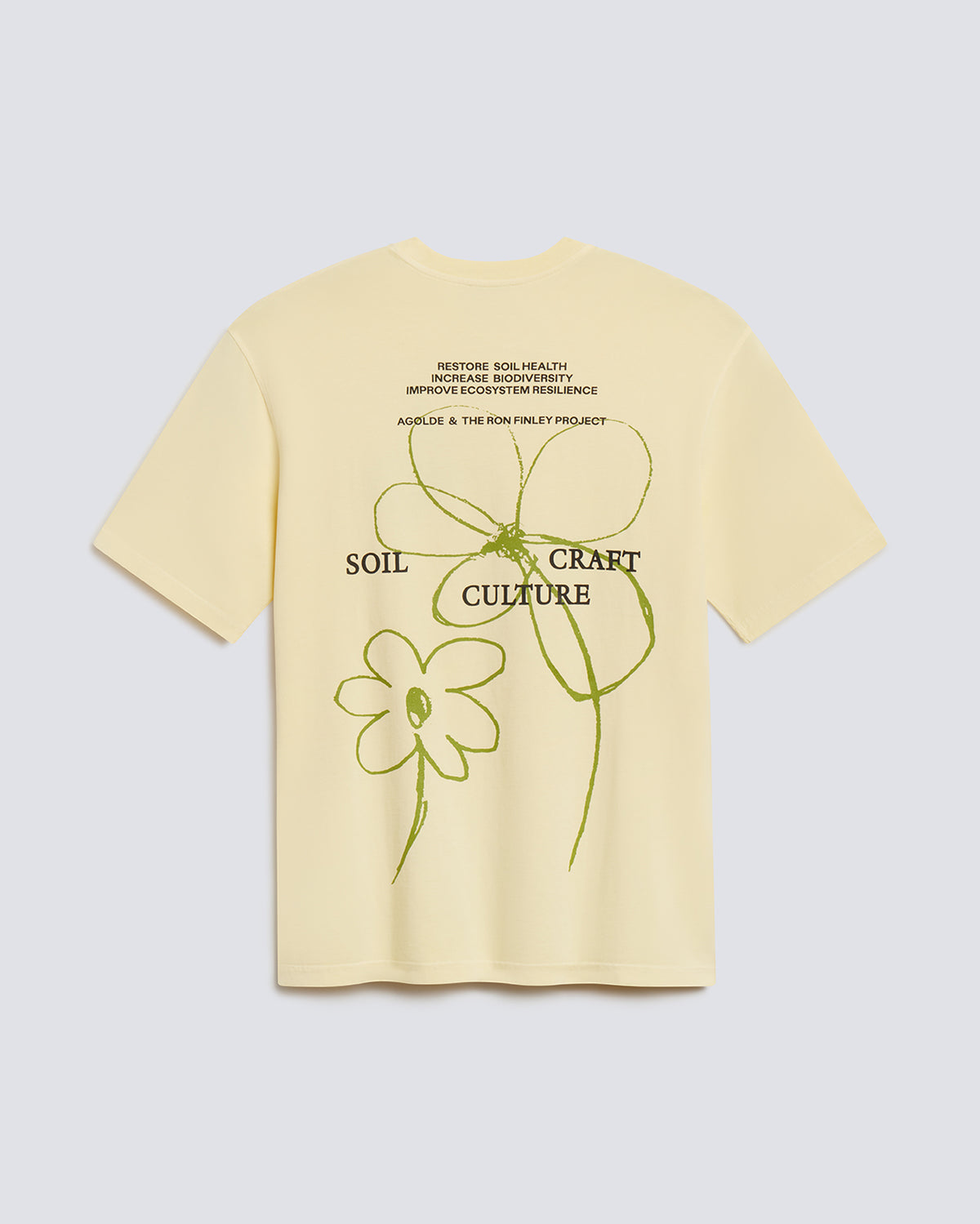 A pale yellow short-sleeve t-shirt shown from the back, featuring a graphic design with green line art of flowers and text that reads 'SOIL CRAFT CULTURE' and 'MISTING SOIL HEALTH.