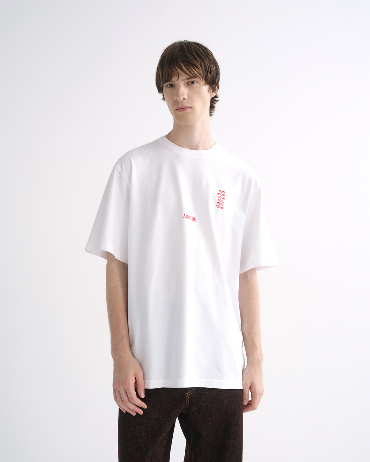 Person wearing a white graphic T-shirt with dark pants on a grey background