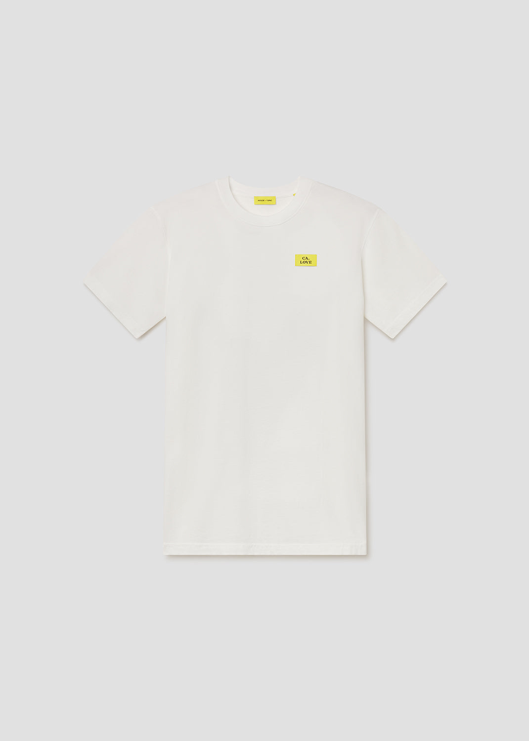 White t-shirt with small yellow labels on a light gray background