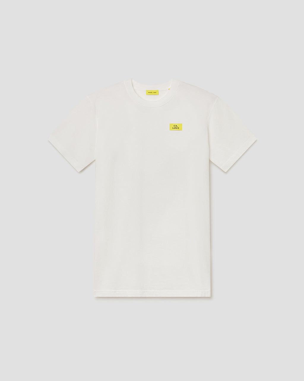 An off-white short-sleeve crewneck t-shirt with a small yellow rectangular logo patch on the left chest, displayed flat against a light gray background.