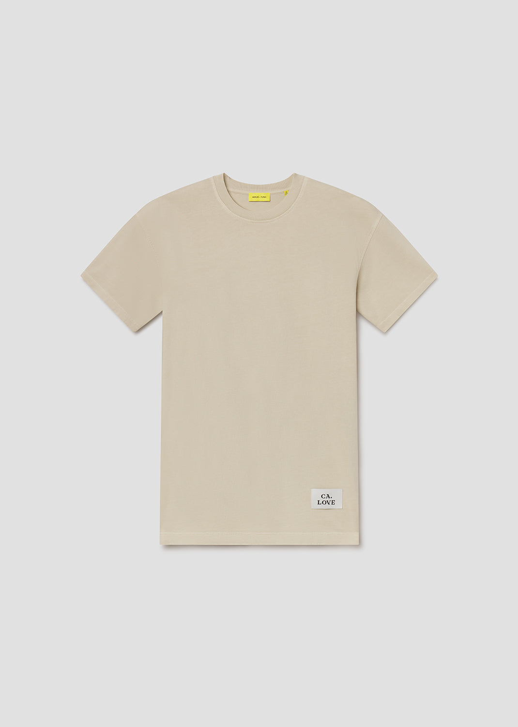 Beige t-shirt with a small label on a light gray background