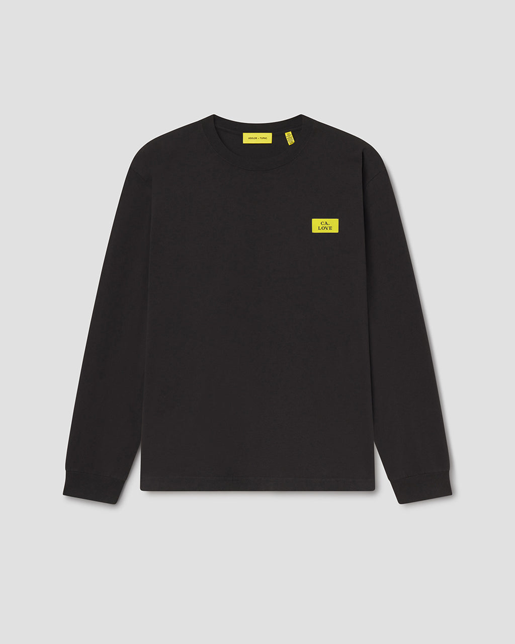 A black long-sleeve crewneck sweatshirt with a small yellow rectangular logo patch on the left chest, displayed on a neutral light gray background.