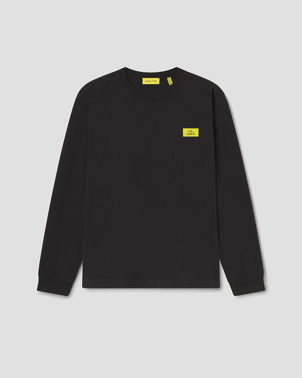 A black long-sleeve crewneck sweatshirt with a small yellow rectangular logo patch on the left chest, displayed on a neutral light gray background.