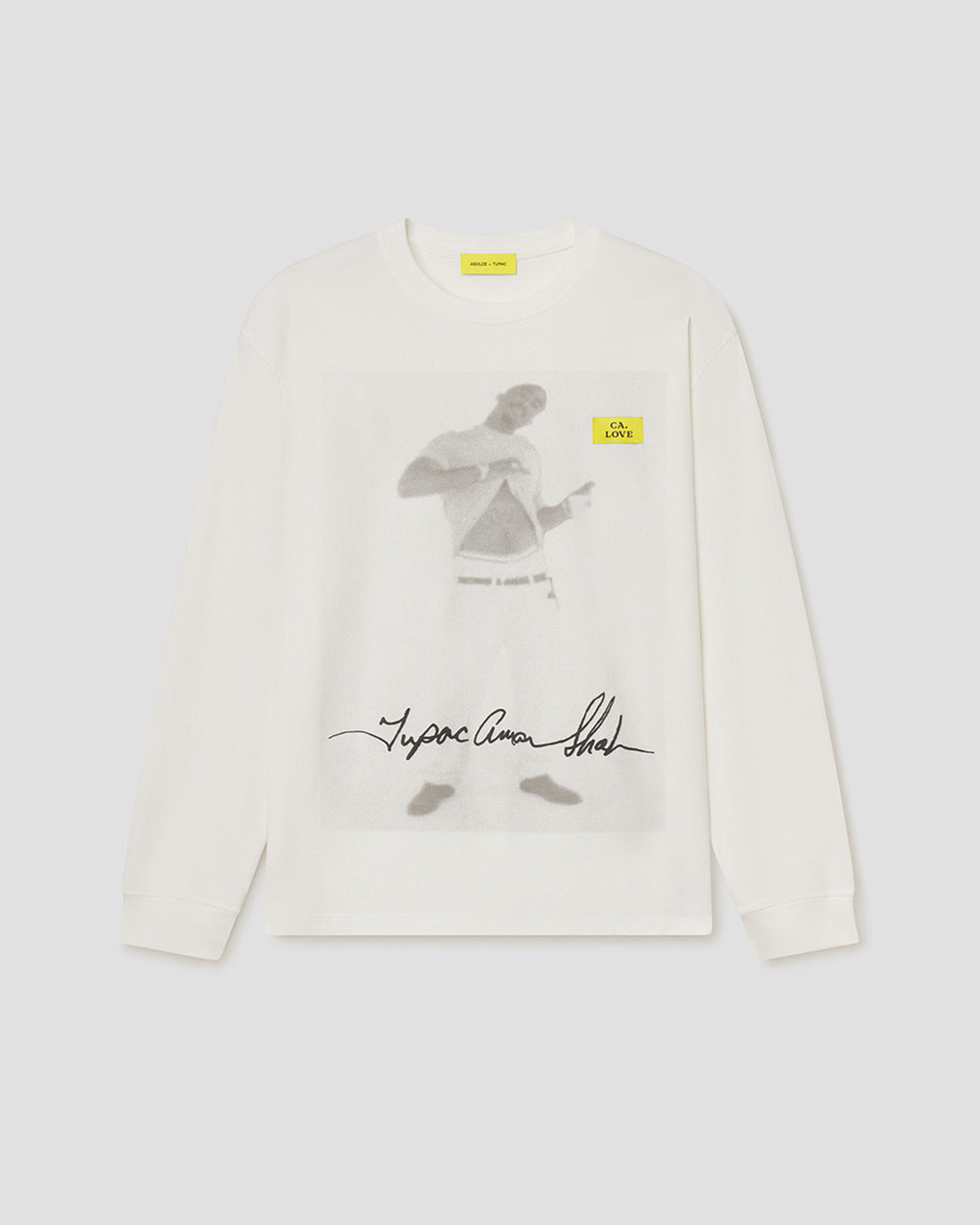 An off-white long-sleeve crewneck sweatshirt featuring a large graphic print of a man on the front, with a small yellow tag on the chest and a signature graphic below.