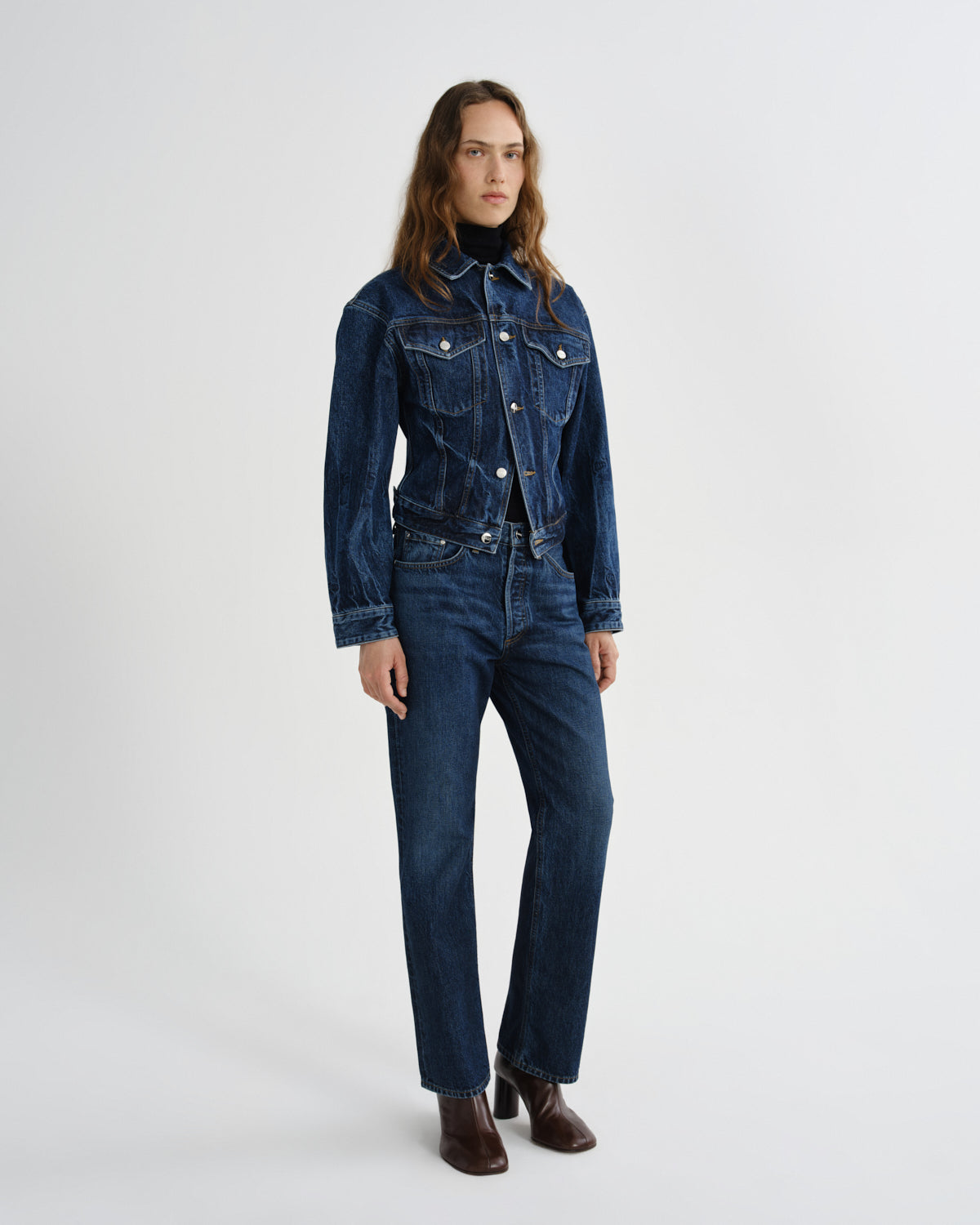 Woman wearing a blue denim jumpsuit on a white background