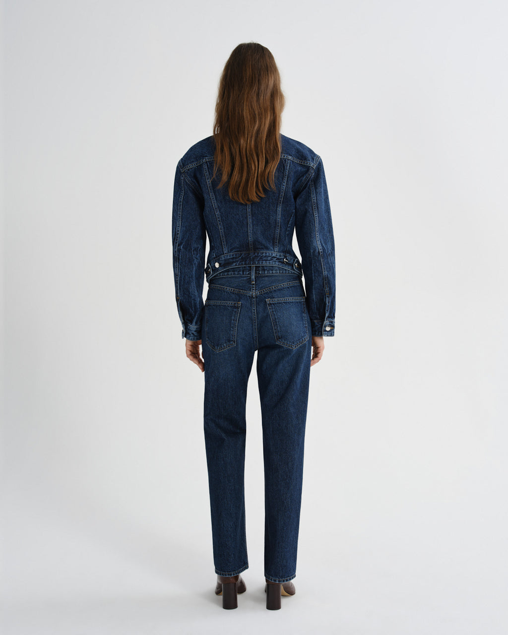 Person wearing a blue denim jumpsuit on a white background