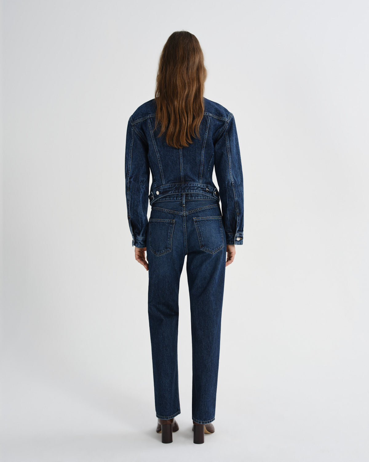 Person wearing a blue denim jumpsuit on a white background