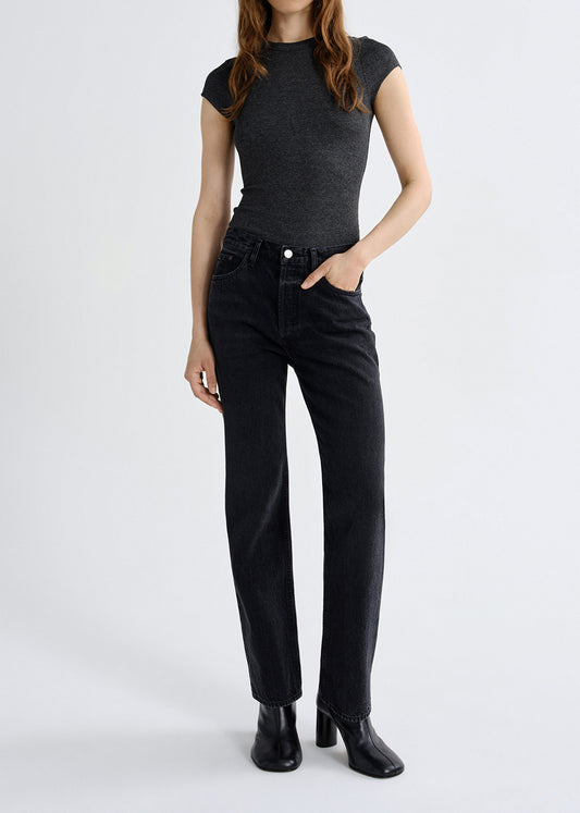 Person wearing a black t-shirt and black jeans on a grey background