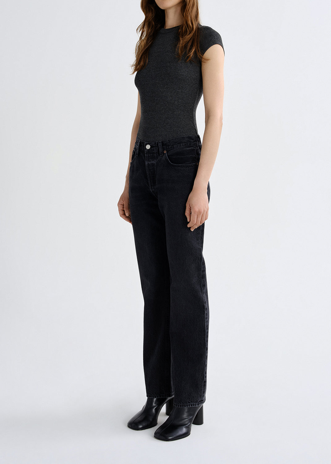 Person wearing a black sleeveless top and black jeans on a grey background