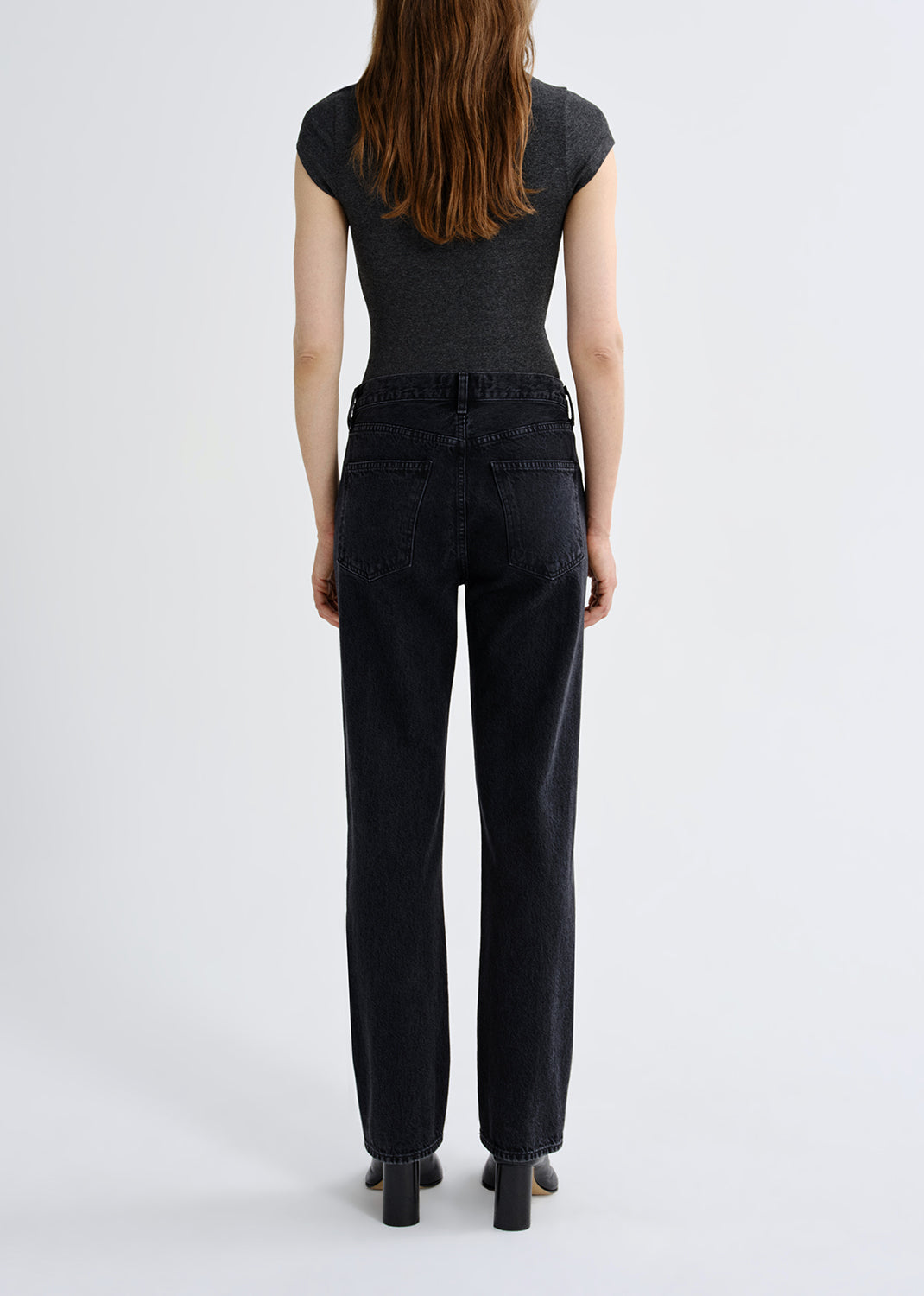 Person wearing a black top and black pants on a grey background