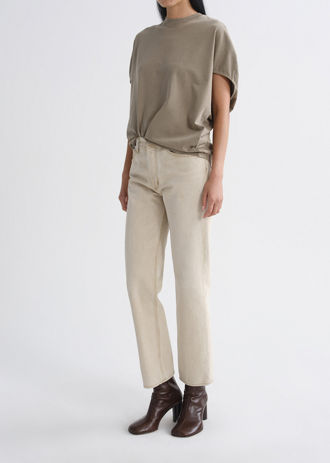 Person wearing a green top and beige pants on a grey background
