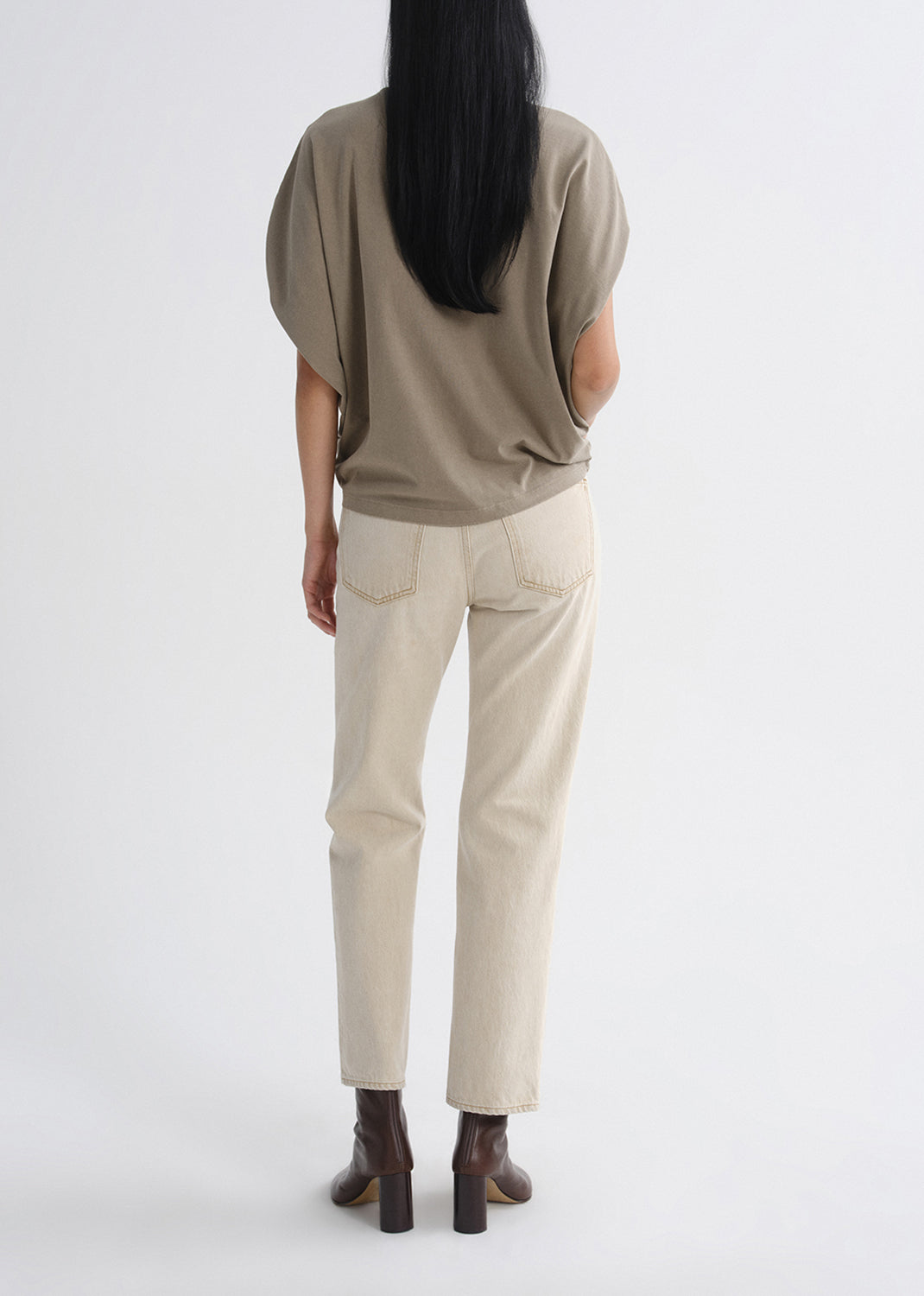 Person wearing a beige top and pants on a grey background