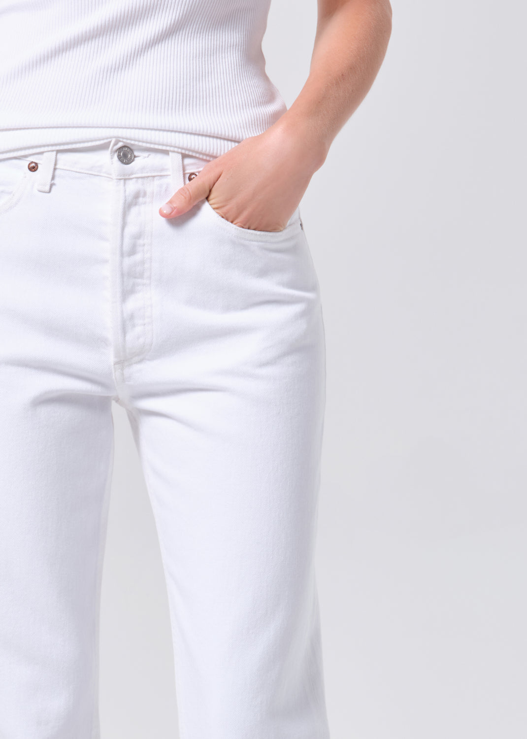 White jeans worn by a person on a light gray background