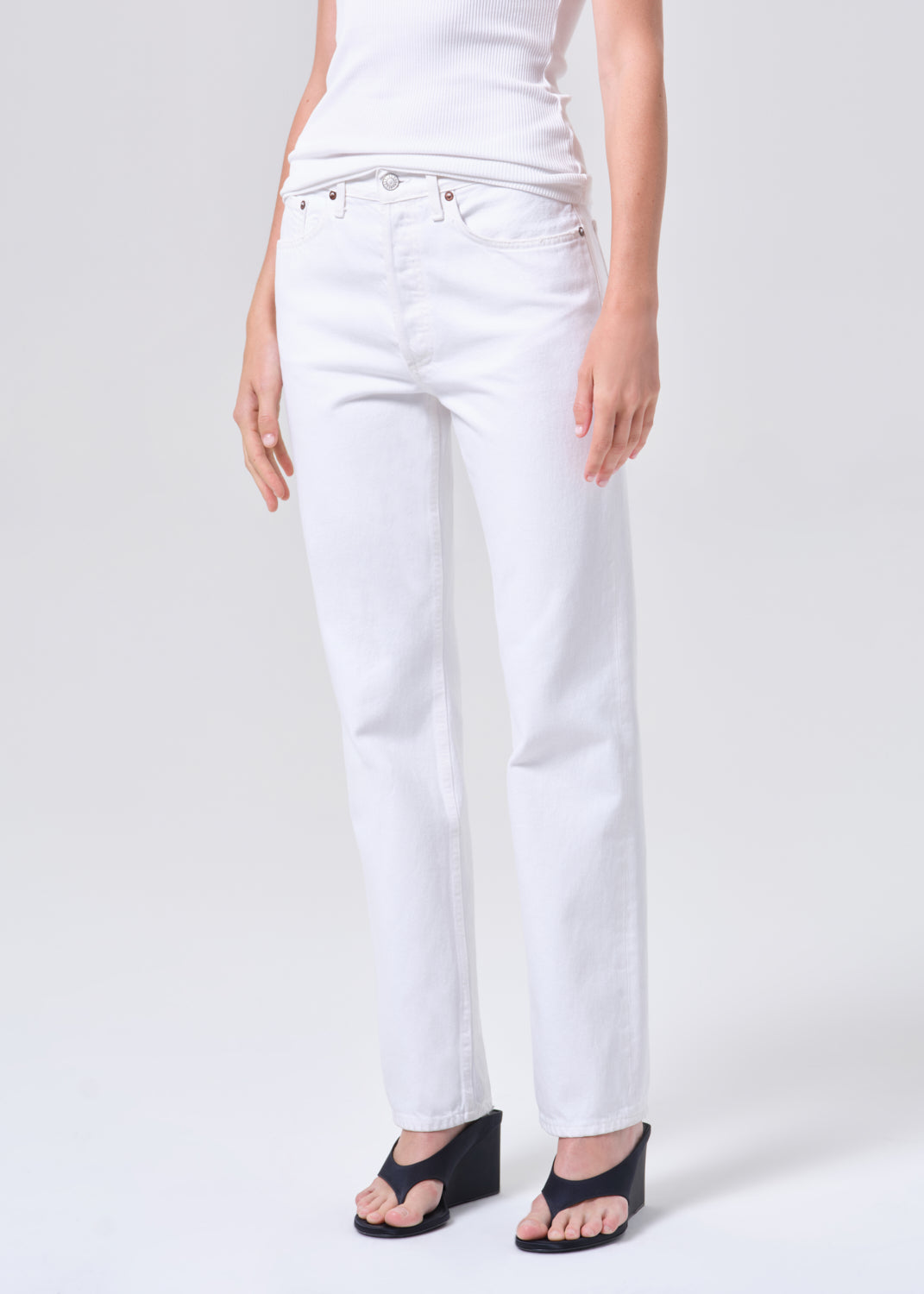 Person wearing white jeans on a plain background