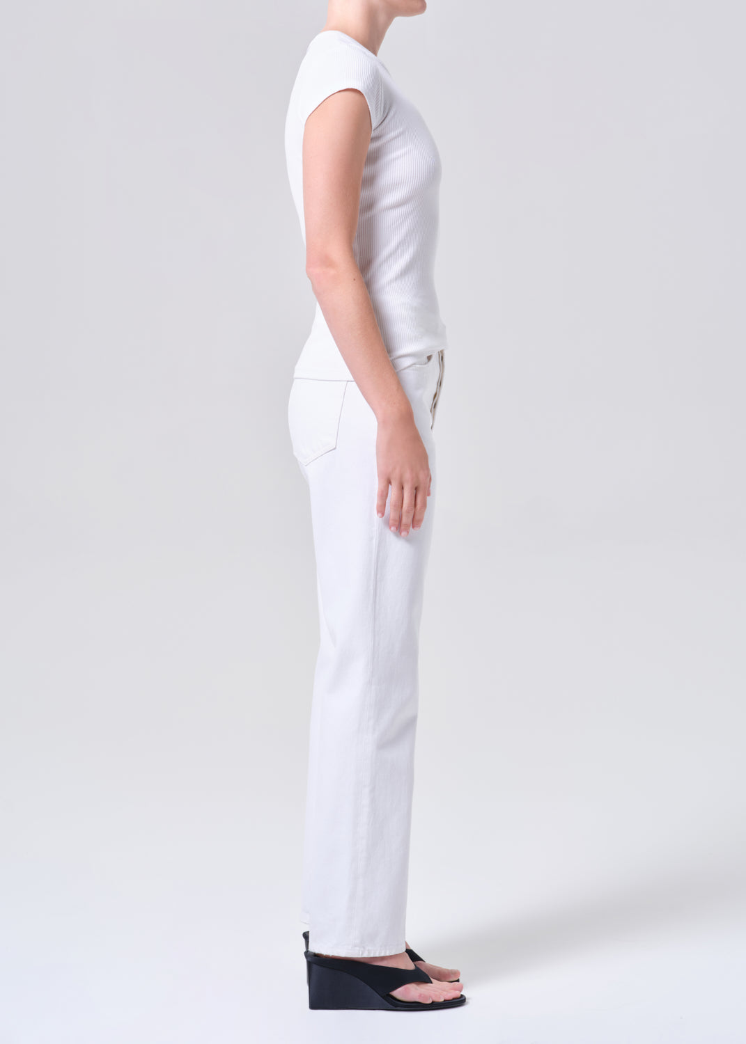 Person wearing a white t-shirt and pants on a plain background