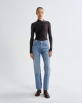 Person wearing a black long-sleeve top and light blue jeans on a white background
