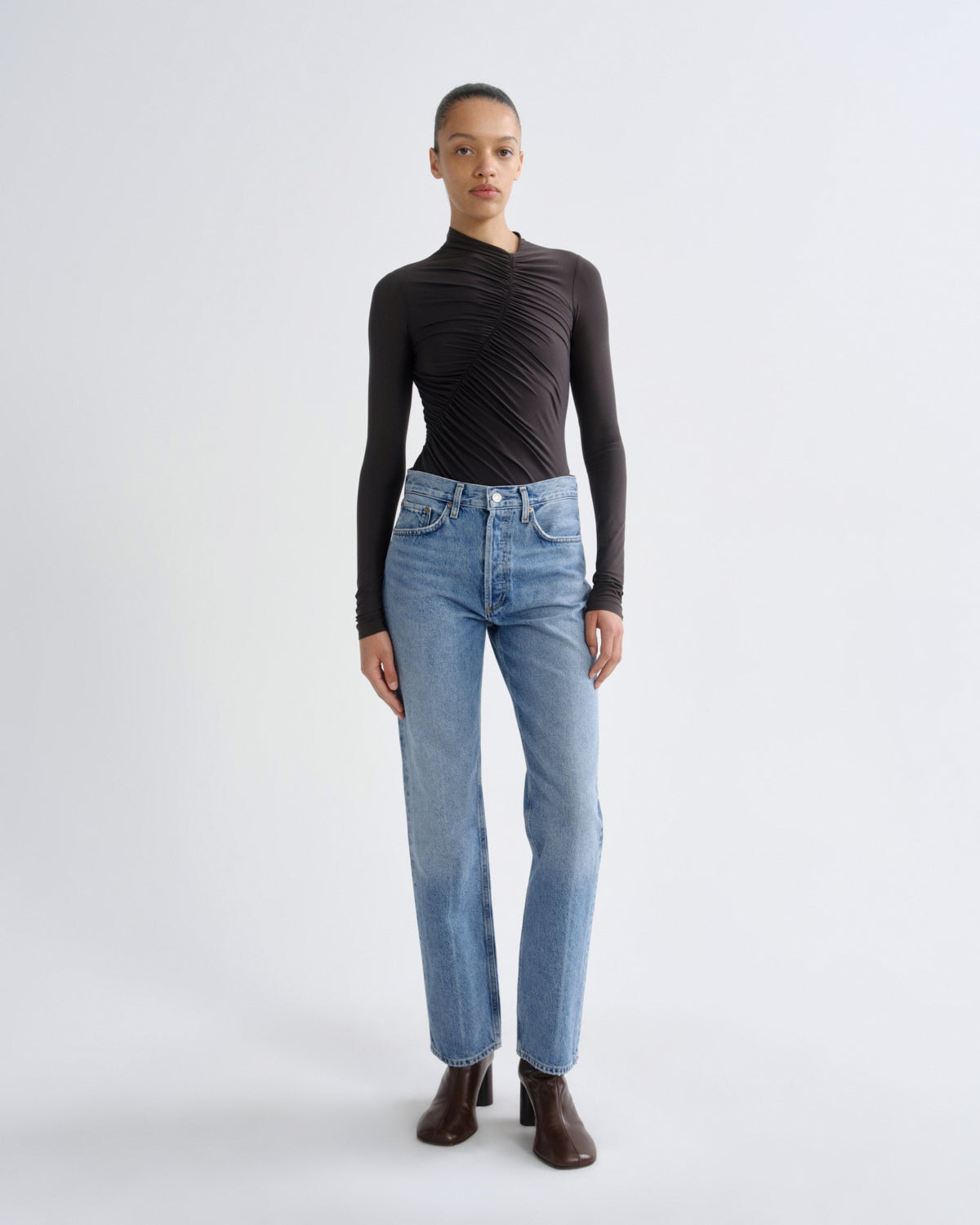 Person wearing a black long-sleeve top and light blue jeans on a white background