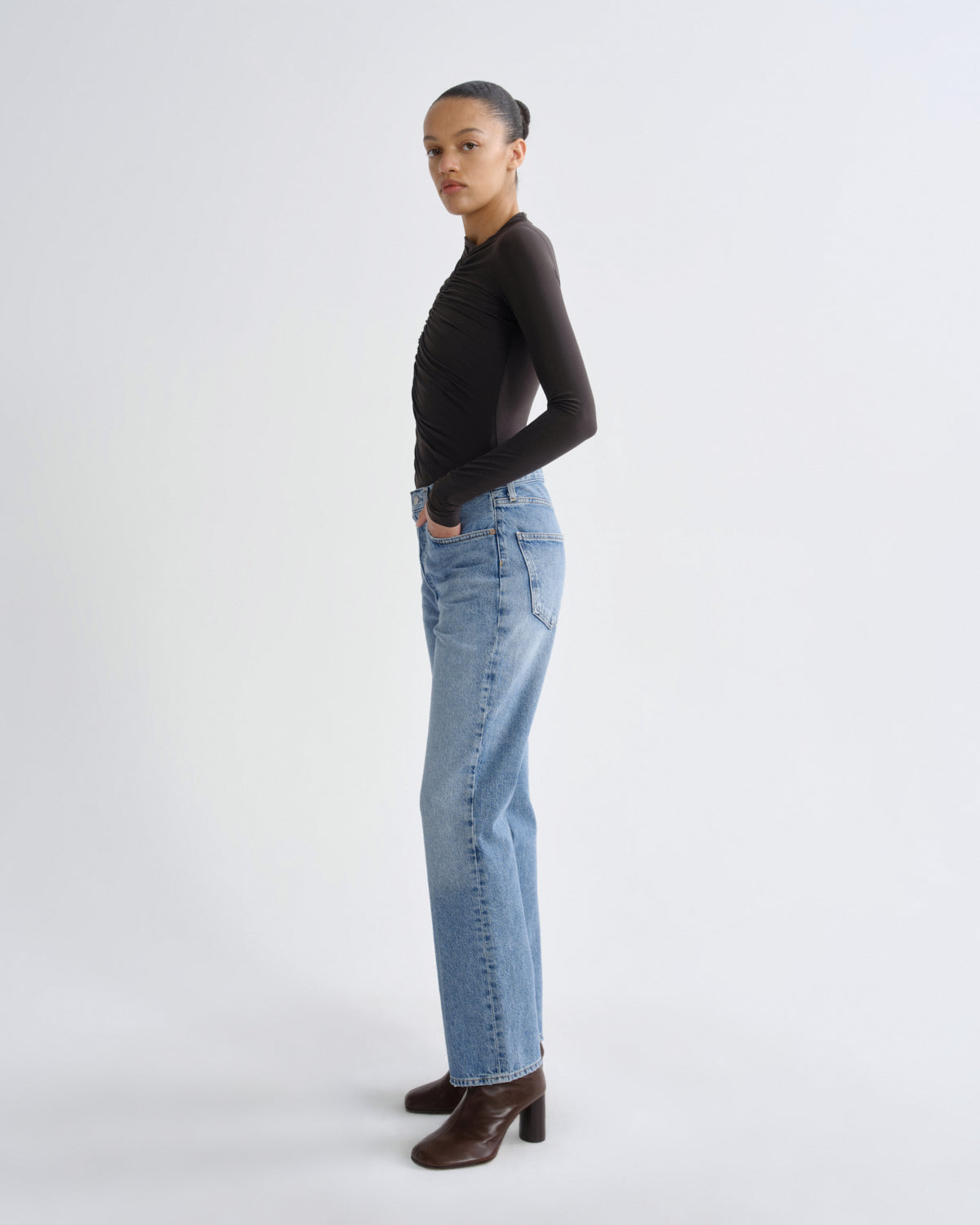 Person wearing a black long-sleeve top and light blue jeans on a white background