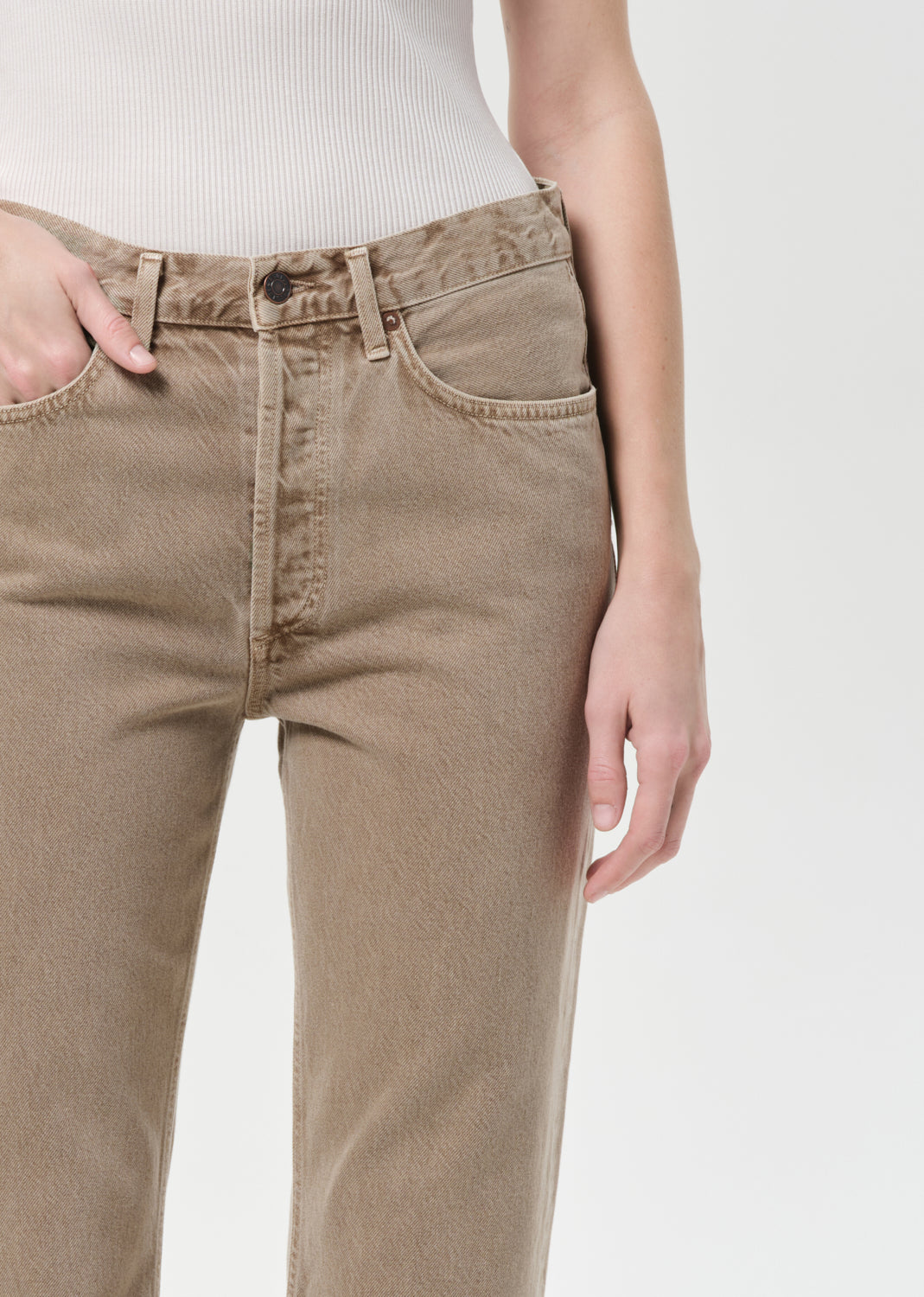 Beige pants worn by a person on a white background