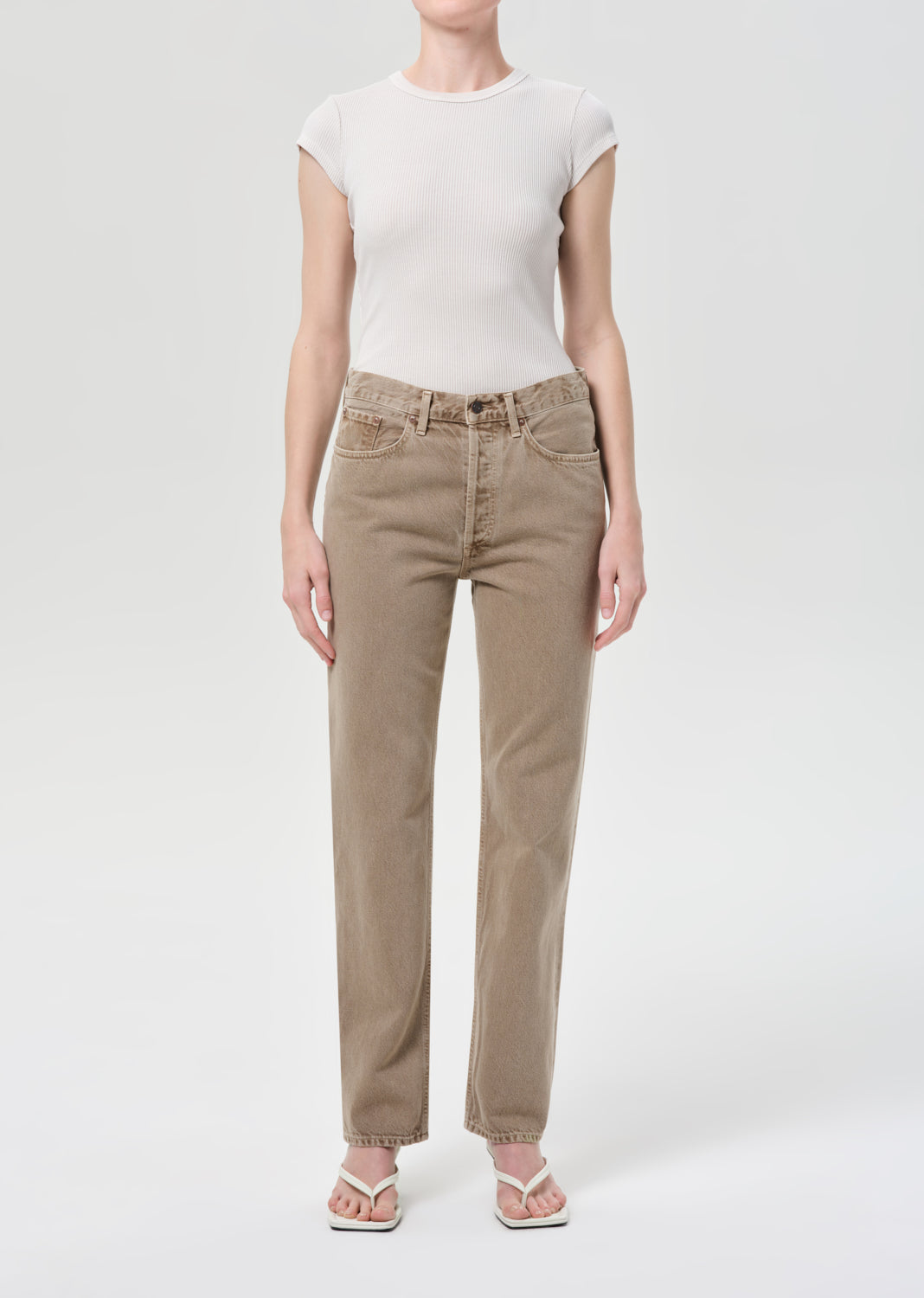Person wearing beige pants and a white top on a white background