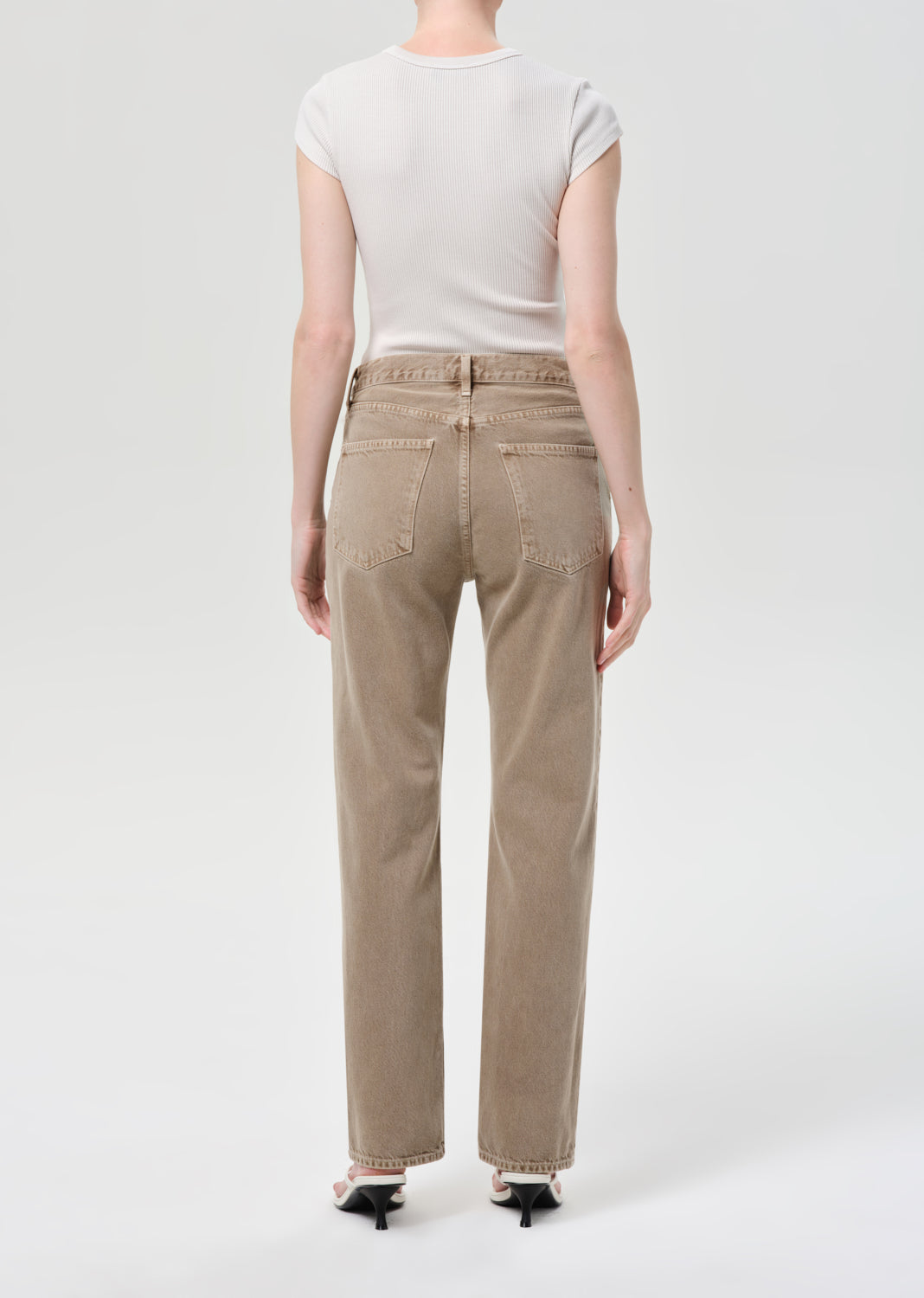 Person wearing beige pants and a white top on a white background