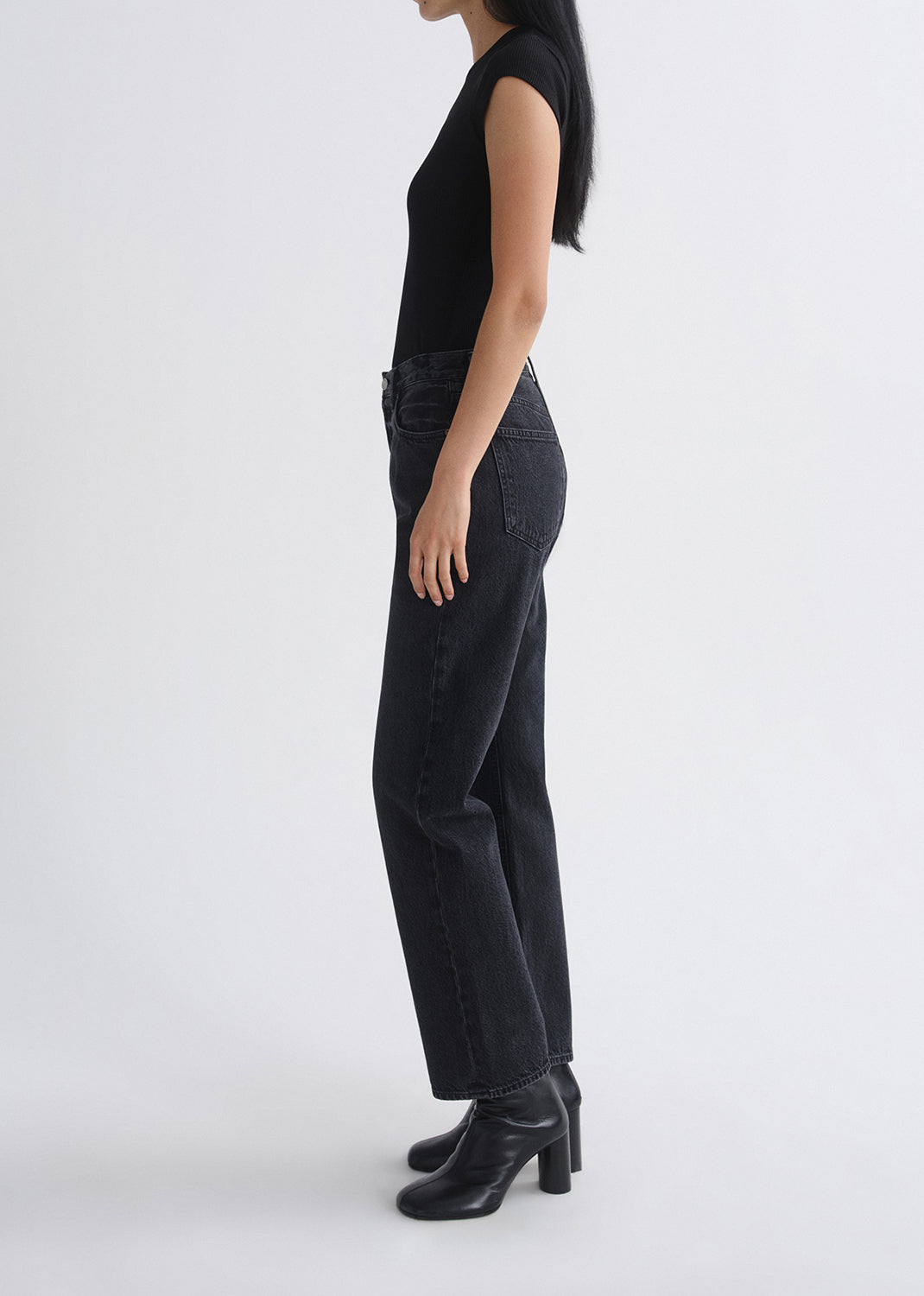 Person wearing black pants and boots on a grey background