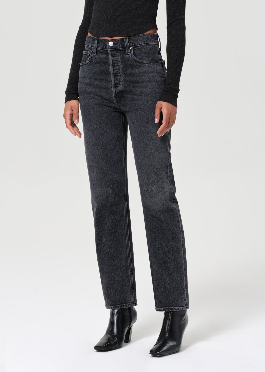 Person wearing black jeans and black boots on a white background