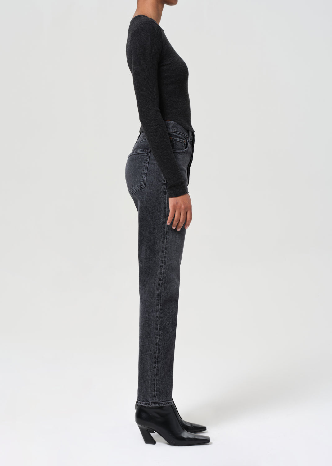 Person wearing black jeans and a black top on a white background
