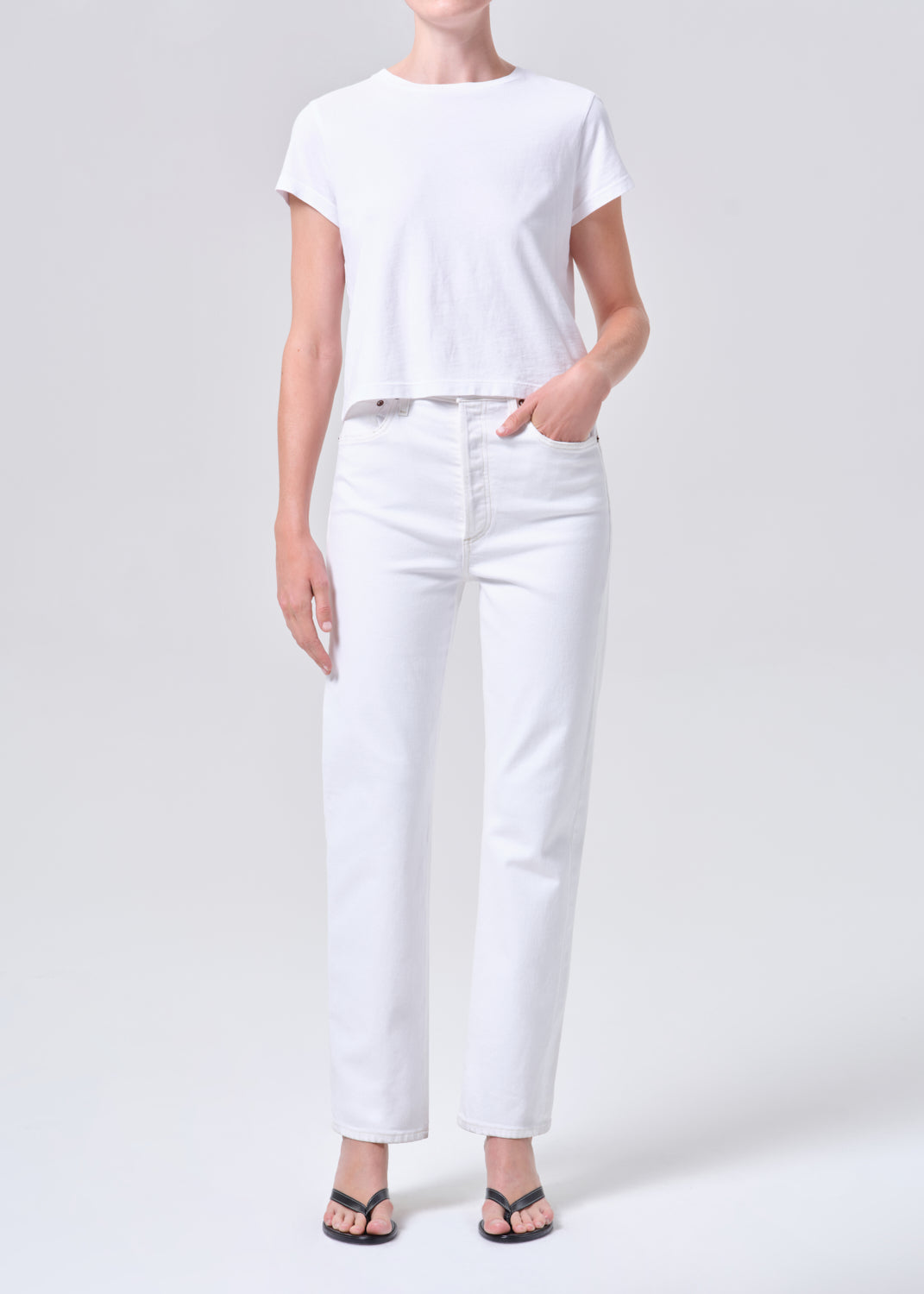 Person wearing a white t-shirt and white pants on a light gray background