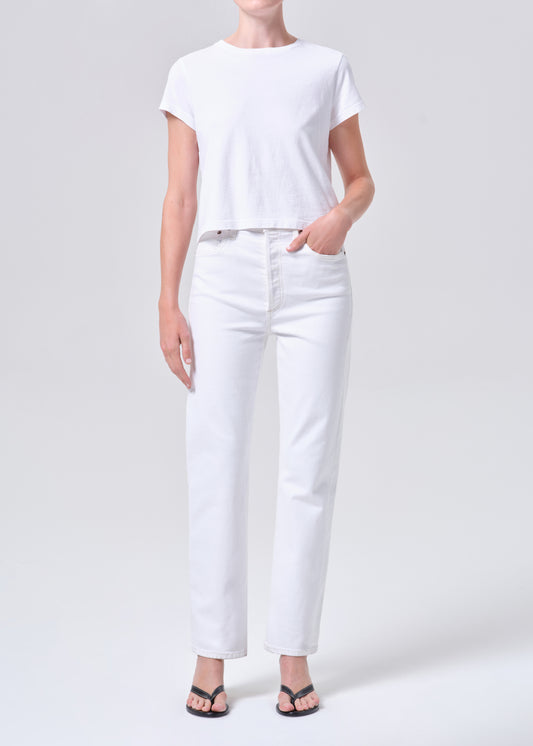 Person wearing a white t-shirt and white pants on a light gray background