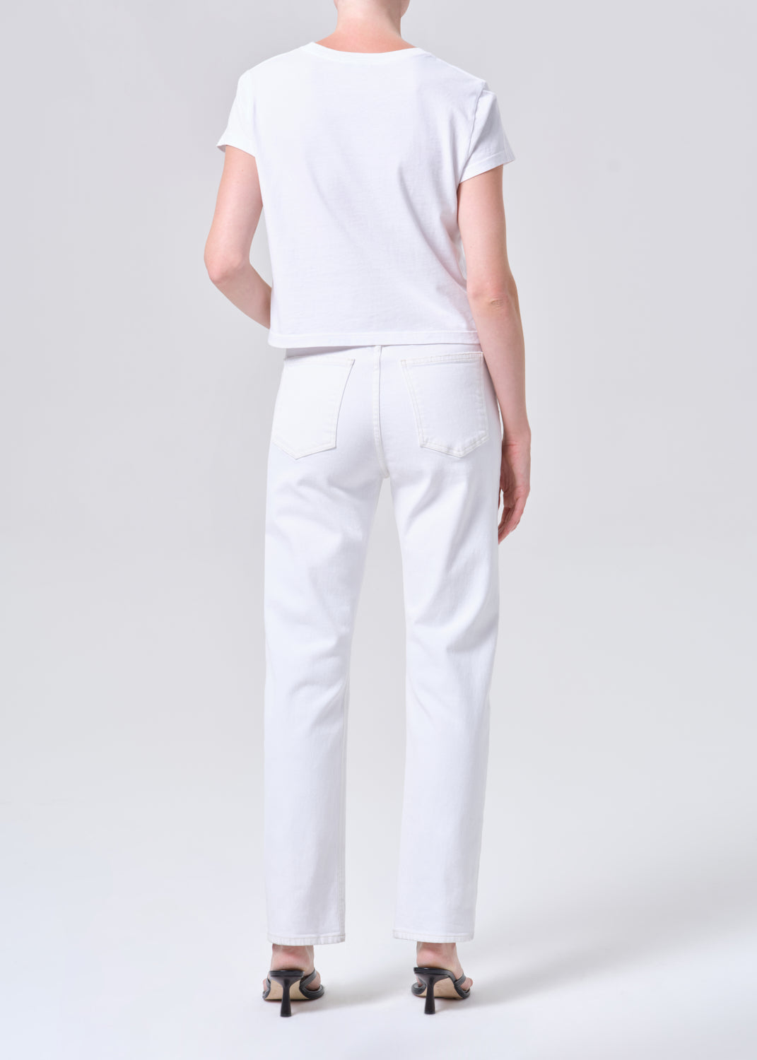 Person wearing a white t-shirt and pants on a light gray background