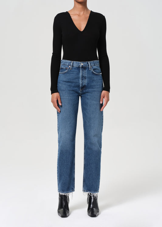 Person wearing a black long-sleeve top and blue jeans on a white background