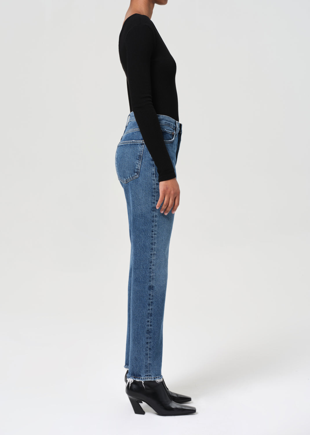 Person wearing blue jeans and a black top on a white background