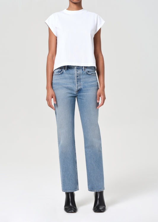 Person wearing light blue jeans and a white top on a white background