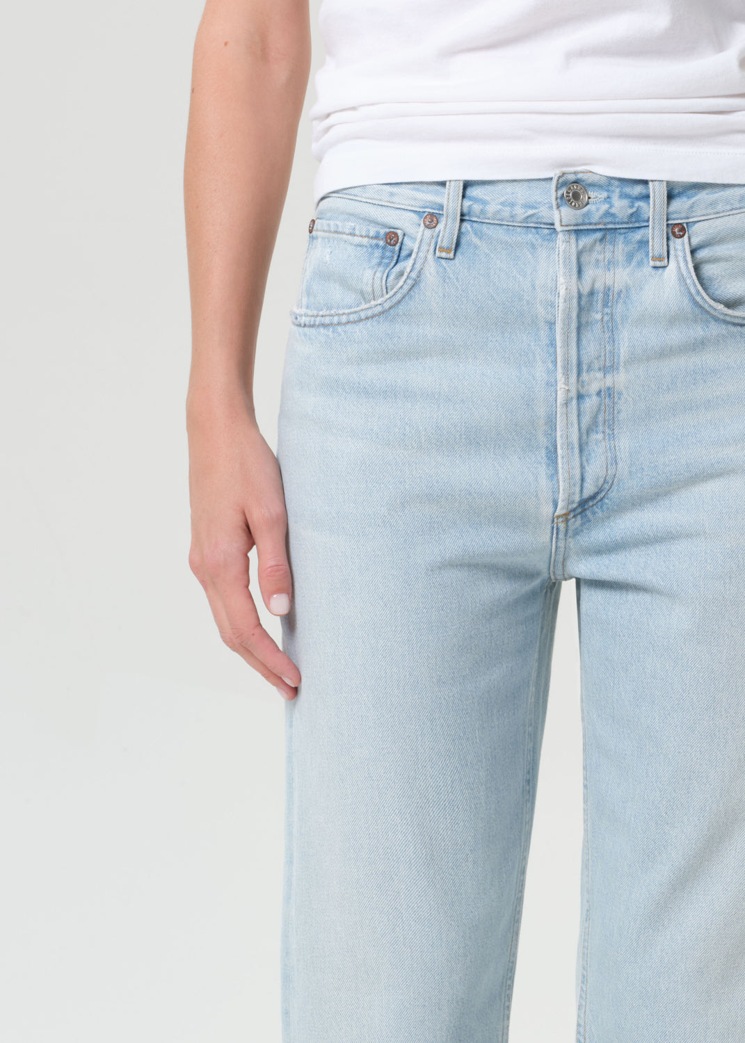 Light blue jeans worn by a person on a plain background