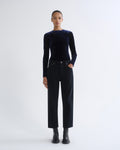Person wearing black long sleeve top and black cropped pants, front view