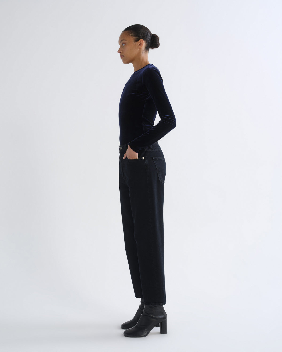 Person wearing black long sleeve top and black cropped pants, side view