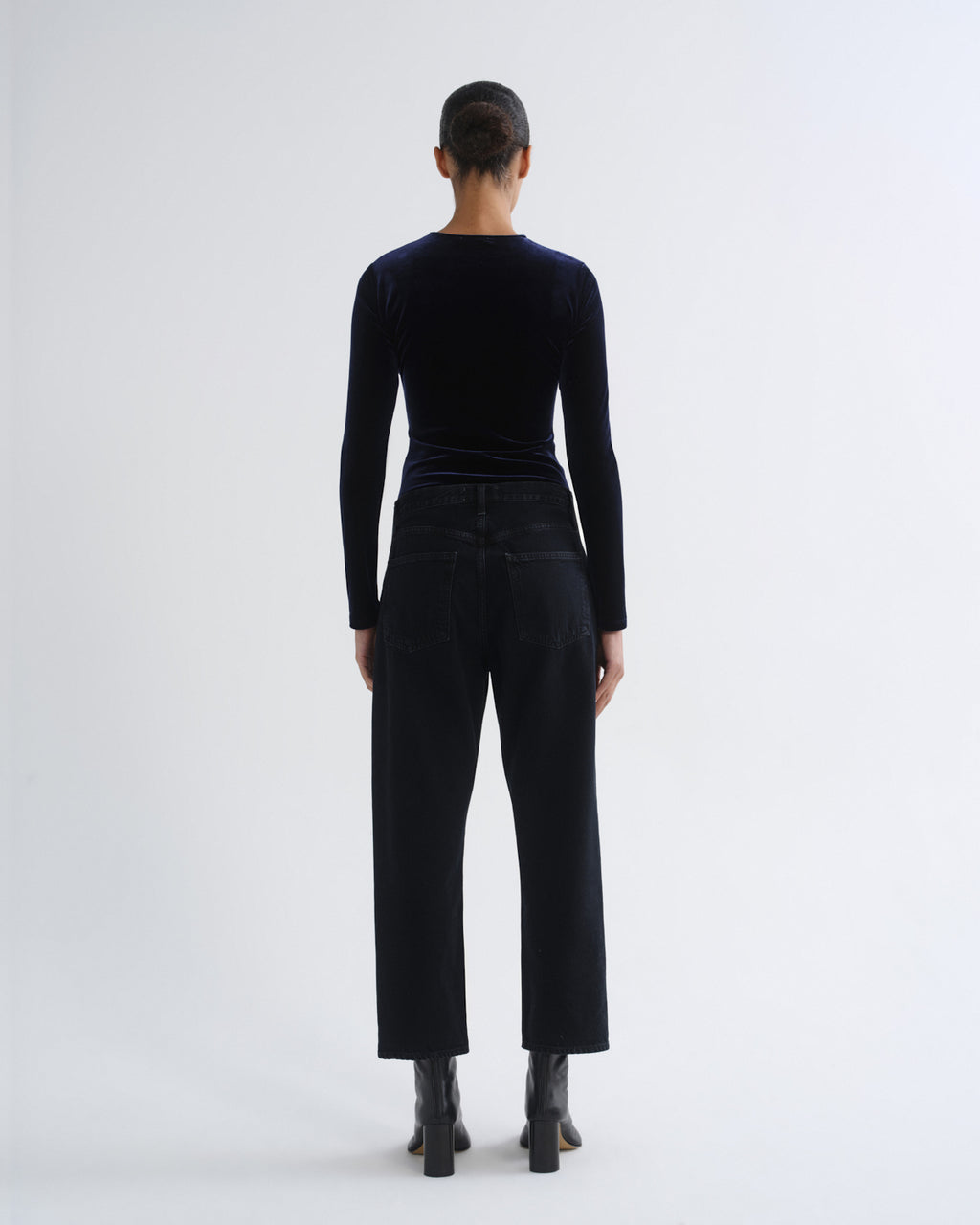 Person wearing black long sleeve top and black cropped pants, back view