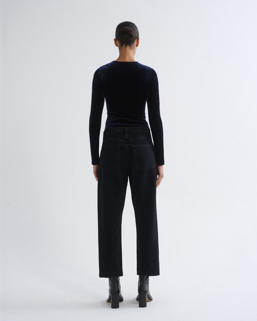 Person wearing black long sleeve top and black cropped pants, back view
