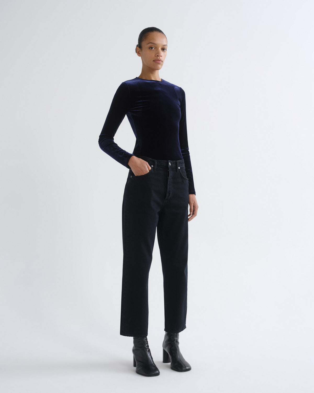 Person wearing black long sleeve top and black cropped pants, front three-quarter view