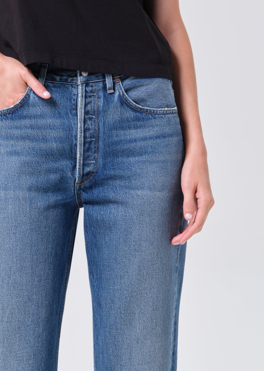 Close-up of blue jeans worn by a person on a white background
