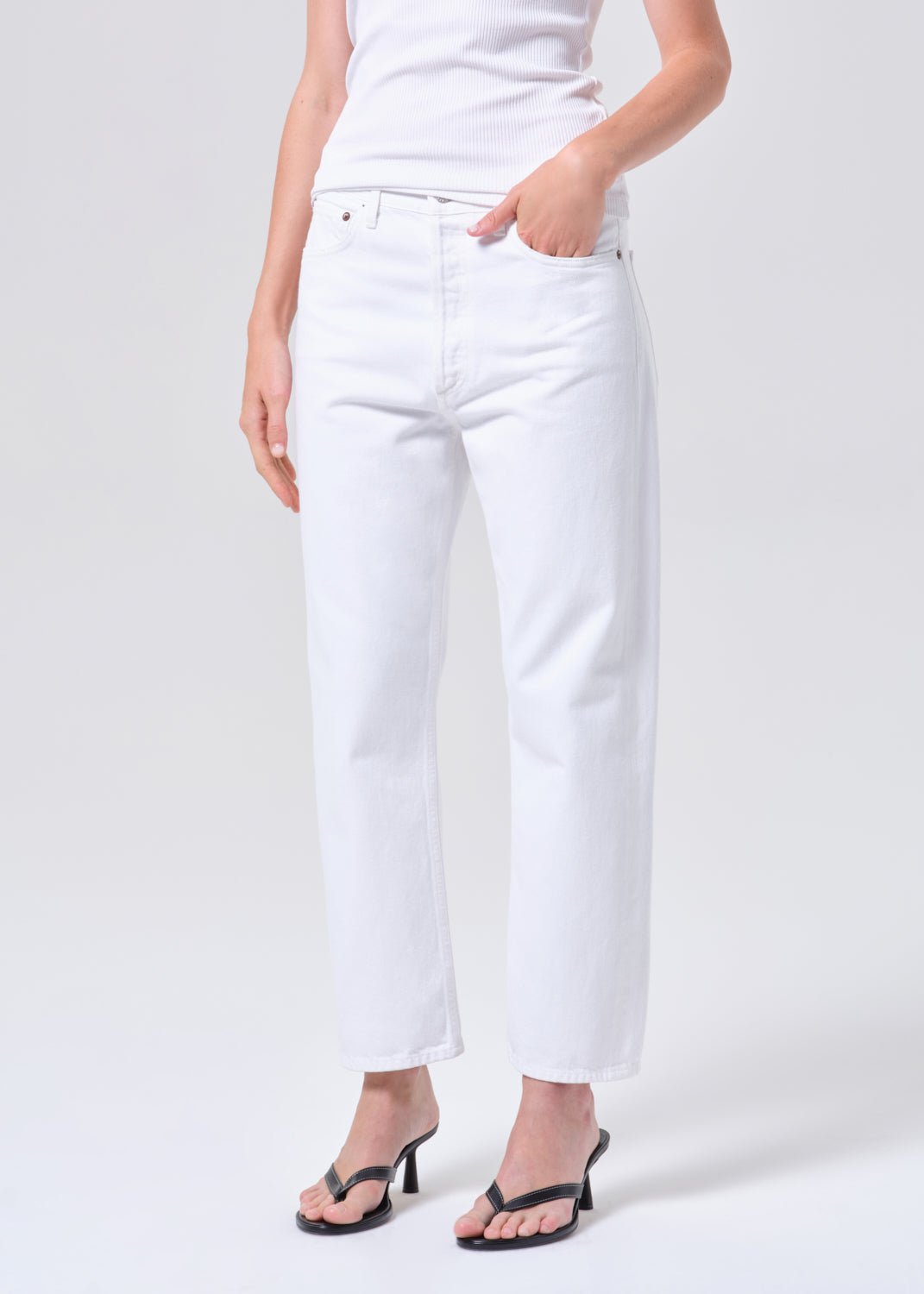 Person wearing white jeans on a plain background