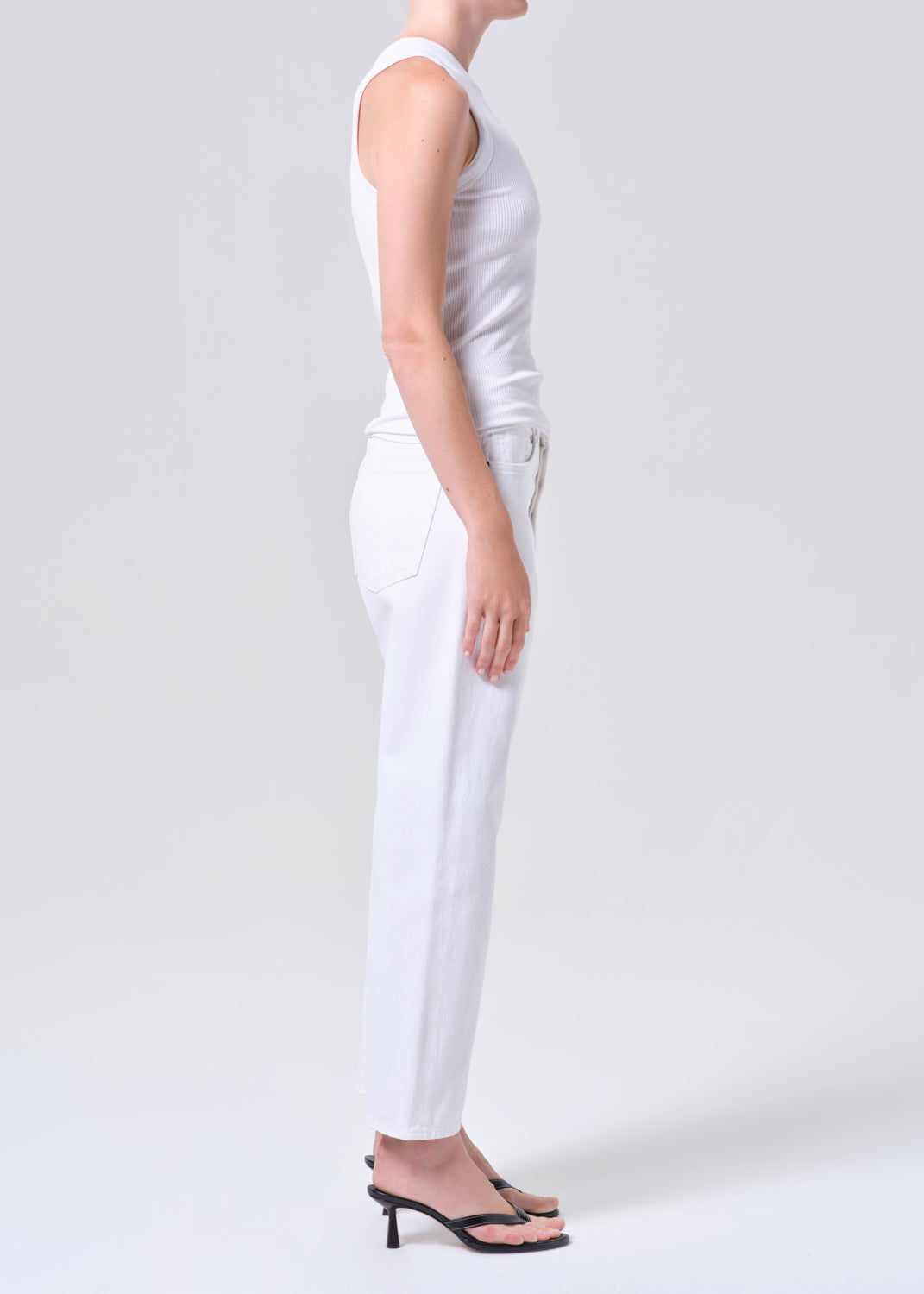 Person wearing a white sleeveless top and pants on a plain background